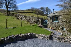 a stone house with a stone wall next to a field at The Bothy at Woodend with Views of Scafell in Broughton in Furness