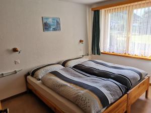 a bed sitting in a room with a window at Ferienhaus Antigua in Saas-Grund