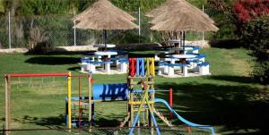 un parque con parque infantil con sillas, mesas y sombrillas en Hotel Termales El Batan, en Cuítiva