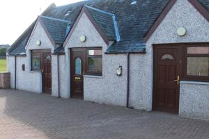 una casa con puertas marrones y una entrada de ladrillo en The Barn Lodge, en Stirling