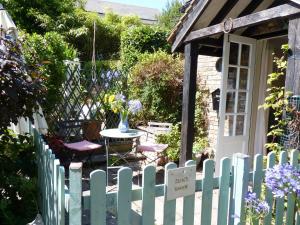 a white picket fence with a table and chairs in a garden at Secret Garden Hideaway For Adults in Eastbourne