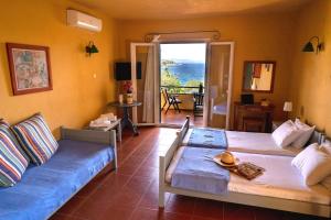 a bedroom with two beds and a blue couch at The Yellow Houses in Ayios Nikolaos Sithonia