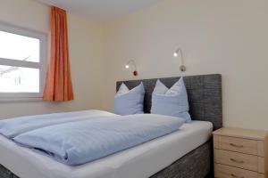 a bedroom with a bed with blue sheets and a window at Vineta Ferienpark Usedom in Koserow +32 photos