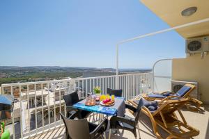 uma varanda com uma mesa e cadeiras num telhado em Summer Breeze apartment with terrace with Panoramic views - by Getawaysmalta em Mellieħa