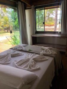 dwa łóżka z białą pościelą w pokoju z oknem w obiekcie Pôr do Sol Eco Suítes w mieście Barra Grande