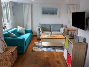 ein Wohnzimmer mit einem blauen Sofa und einem TV in der Unterkunft Furneaux Hatch in Kingsbridge