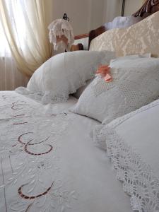 un letto bianco con cuscini bianchi ricamati sopra di B&B Palazzo Mestichelli Boutique Palace a Monteprandone