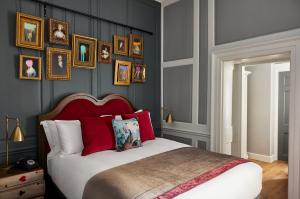 a bedroom with a bed with red pillows and pictures on the wall at Hotel Indigo - Bath by IHG in Bath