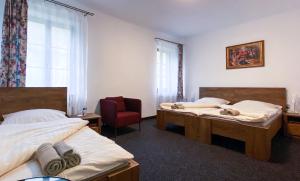 una camera da letto con due letti, una sedia e una finestra di Hotel Sýkora a Křivoklát