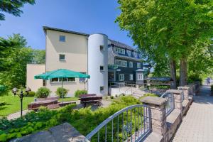 ein Gebäude mit einem Park mit Bänken und einem Regenschirm in der Unterkunft Hotel Haus Oberland in Masserberg