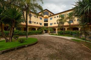 a large building with palm trees and a driveway at Jardin Park Hotel in Jardinópolis