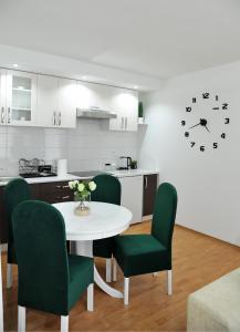 eine Küche mit einem Tisch, Stühlen und einer Uhr in der Unterkunft Apartman Lizdek in Pale