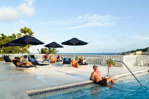 um homem sentado na piscina de um resort em Princess Heights Luxury Condo Hotel em Dawn Beach