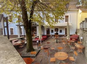 un patio con mesas, sillas y un árbol en Hotel Sýkora, en Křivoklát