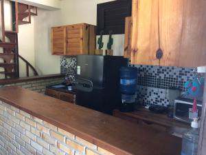 a kitchen with a black refrigerator and a brick wall at Casa YeS Jeri in Jericoacoara