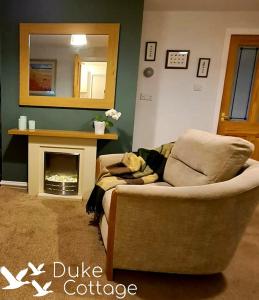 a living room with a couch and a fireplace at Duke Cottage in Fochabers