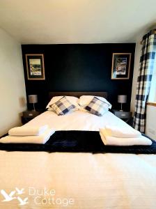 a bedroom with a large bed with two pillows at Duke Cottage in Fochabers