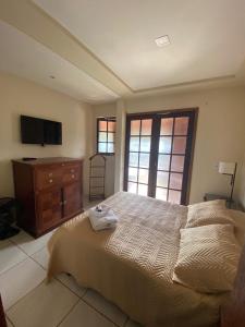 a bedroom with a bed and a dresser and a television at Pousada Village Tere in Teresópolis