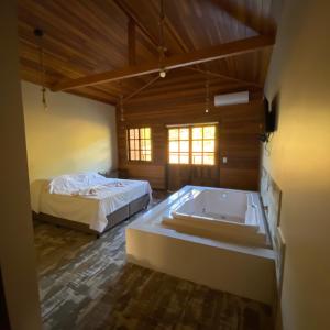 a large room with a tub and a bed at Pousada Recanto Pomerano in Pomerode