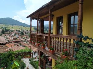 a yellow house with potted plants on a balcony at Емили Фемили Хаус in Koprivshtitsa