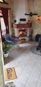 a living room with a fireplace and a chair at OAZA KUĆA ZA ODMOR in Čurug
