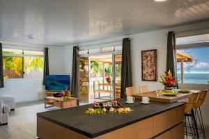 Il comprend une cuisine et un salon avec une table et des chaises. dans l'établissement Matira Sandy Home 658 DTO-MT, à Bora Bora