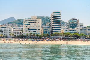 un grupo de personas en una playa con edificios en Hotel Arpoador, en Río de Janeiro