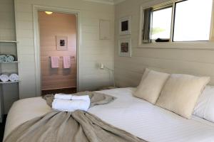 ein Schlafzimmer mit einem Bett mit zwei Handtüchern darauf in der Unterkunft BINALONG BEACH COTTAGE Beachfront at Bay of Fires Next to Restaurant in Binalong Bay
