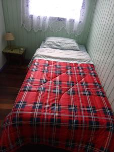 a bed in a room with a red plaid blanket at Casa Santos Dumont in Gramado