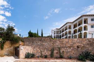 Hotel Quinta Las Fuentes Bernal في برنال: مبنى خلف جدار حجري فيه صبار