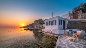 a sunset over the water next to a building at On The Rocks in Symi