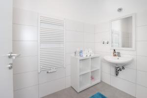 La salle de bains blanche est pourvue d'un lavabo et d'un miroir. dans l'établissement Dalila Appartements, à Sankt Michael im Lungau