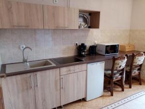 a kitchen with a sink and a counter with chairs at Major Street Apartman in Hajdúszoboszló