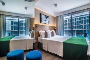 a hotel room with two beds and two blue stools at 360 São Luis in Sao Paulo