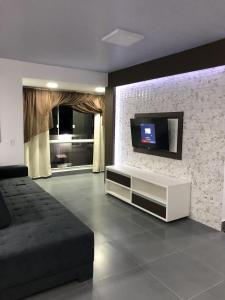 a living room with a tv on a brick wall at Residencial Flat Debora in Florianópolis