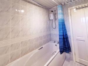 a white bath tub in a bathroom with a blue shower curtain at Noknokstay-Highstone House,4 Bedrooms, Garden with Parking, Great for Longer Stay in Barnsley +25 photos