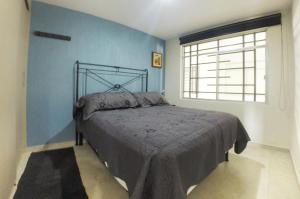 a bedroom with a bed with a blue wall at Hospedaje Tlaquepaque in Guadalajara
