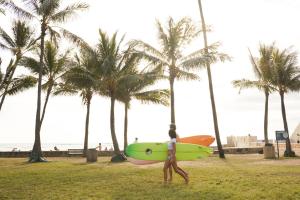 
a woman walking across a lush green field holding an umbrella at Stay Hotel Waikiki in Honolulu
