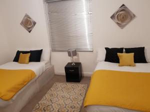 two beds in a room with yellow and black pillows at Bambz Apartment 2 in Manchester