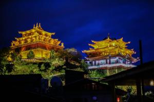 Arro Khampa By Zinc Journey Shangri-la في شانغريلا: مبنيان صينيان على تلة في الليل