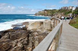 a boardwalk along the ocean with people walking on the beach at PodBed Coogee Beachside in Sydney