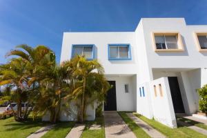 a white house with palm trees in front of it at Casa STB01 con Alberca a 5 min de Nuevo Vallarta in Mezcales