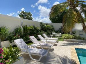a group of white lounge chairs and a swimming pool at Yoyita Suites Aruba in Palm-Eagle Beach