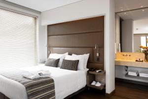 1 dormitorio con 1 cama blanca grande y espejo en bs Rosales Hotel, en Bogotá