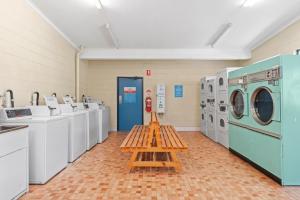 a laundry room with washing machines and a wooden shelf at Discovery Parks - Jindabyne in Jindabyne