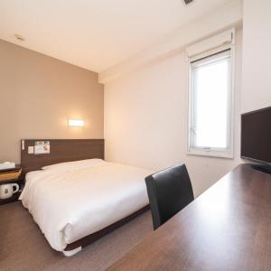 a bedroom with a bed and a desk and a television at Super Hotel JR Fujiekimae Kinenkan in Fuji