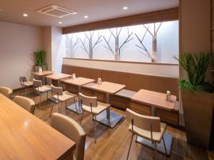 富士的住宿－Super Hotel JR Fujiekimae Kinenkan，餐厅设有桌椅和大窗户。