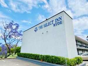 un bâtiment blanc avec un panneau sur son côté dans l'établissement The Select Inn Ryde, à Sydney