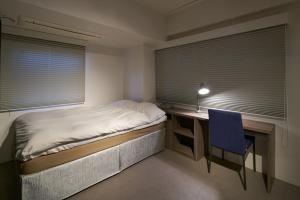 東京にあるシティホテル エヌ.ユー.ティ.エスのベッドルーム1室(ベッド1台、デスク、青い椅子付)