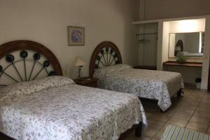ein Hotelzimmer mit 2 Betten und einem Spiegel in der Unterkunft Chacala Caracoles 6 pax AA con ALBERCA y PLAYA a 50 mts in Chacala